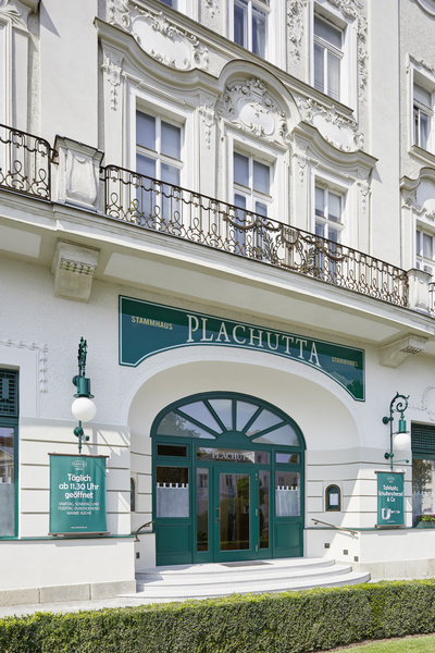 Nahaufnahme einer grünen Holztür mit diagonalen Paneelen und sichtbaren Anzeichen von Abnutzung und abblätternder Farbe.