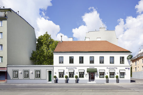 Modern wooden pergola with seating on a lawn, with sunlight streaming through the slatted roof.
