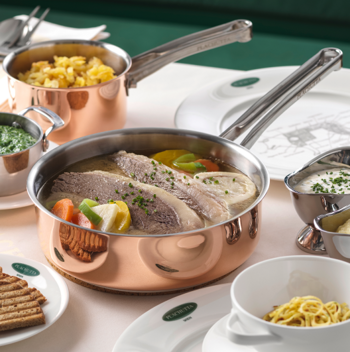 Ein alter Laternenpfahl steht inmitten blühender lila und rosa Blumen in einem Garten.